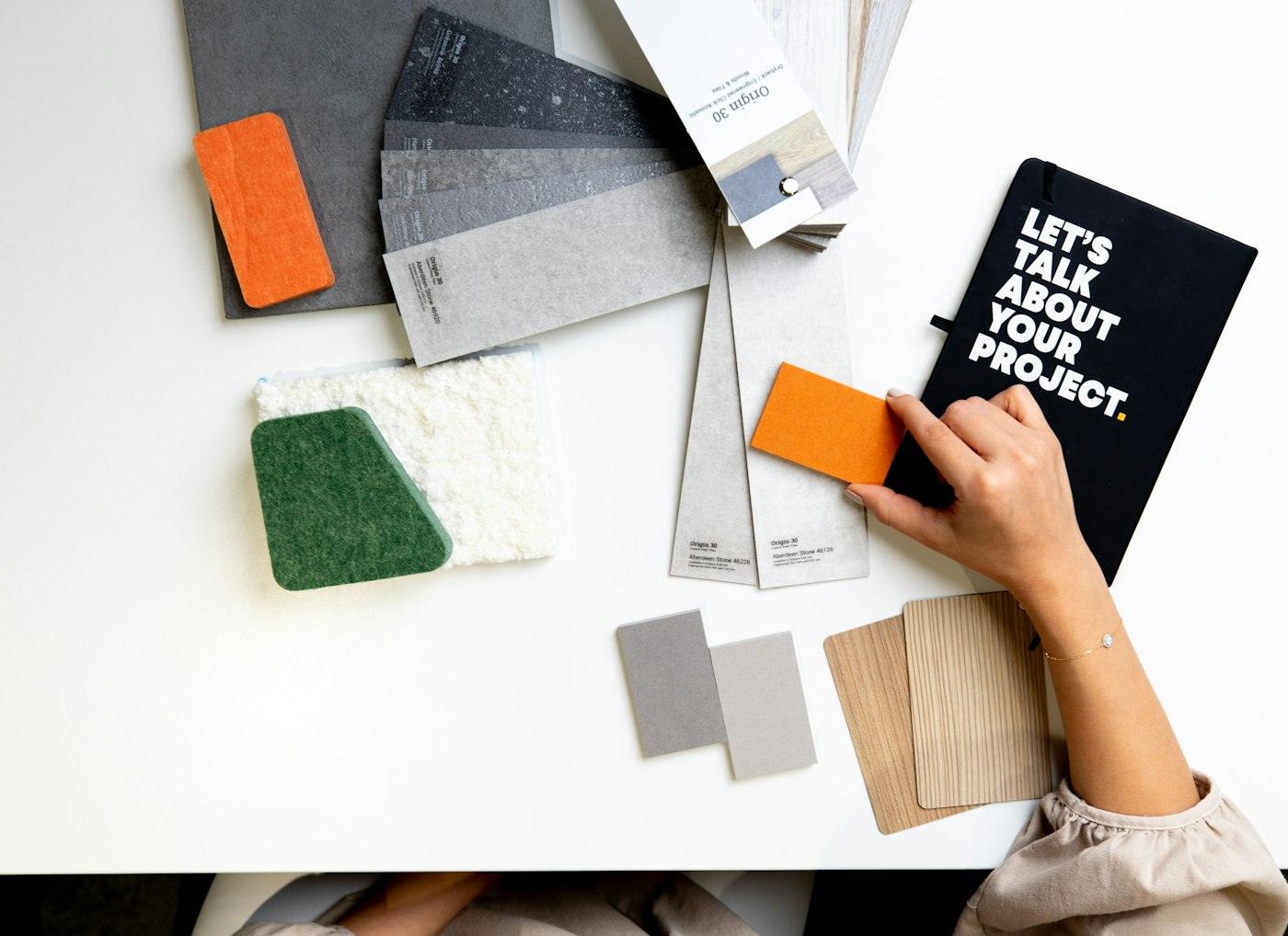 Hands choosing colour and material samples on a desk