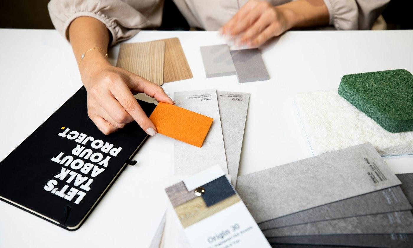 A designer sketching ideas on paper beside material samples
